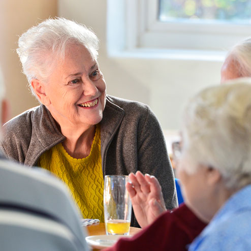 Senior woman chatting with friends at Waterbeach community room