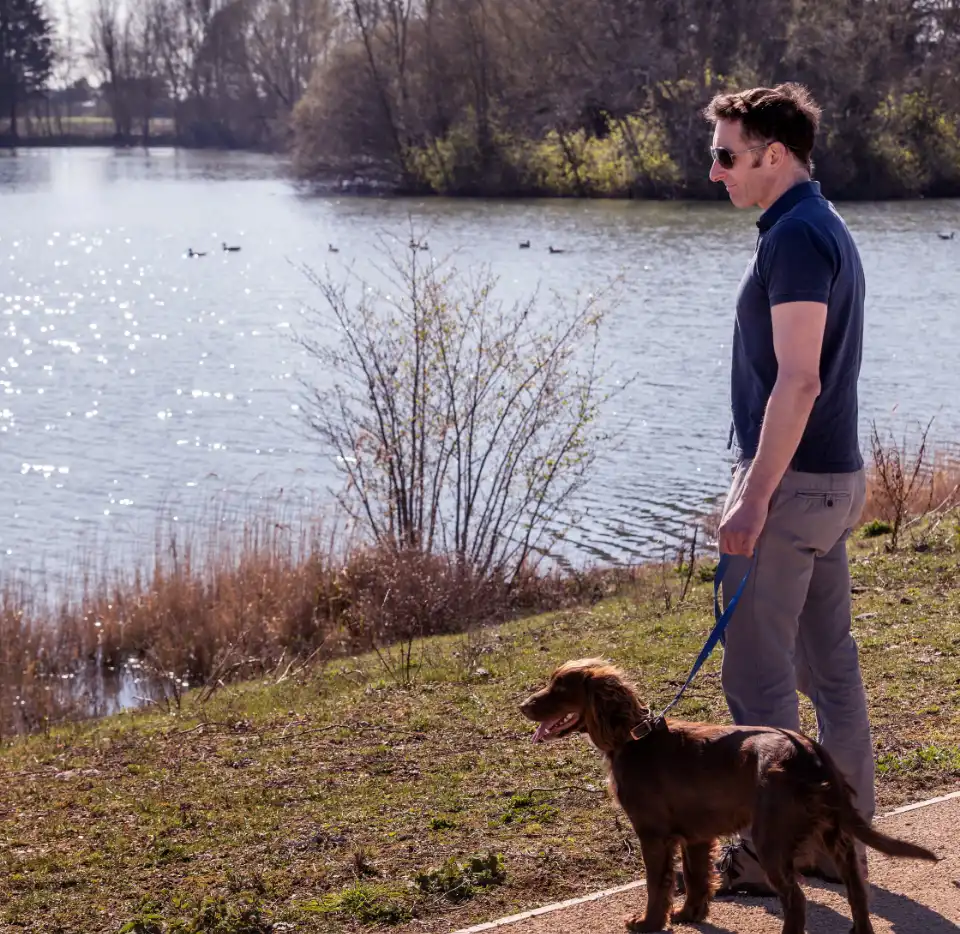 A man and his dog, standing looking at the lake