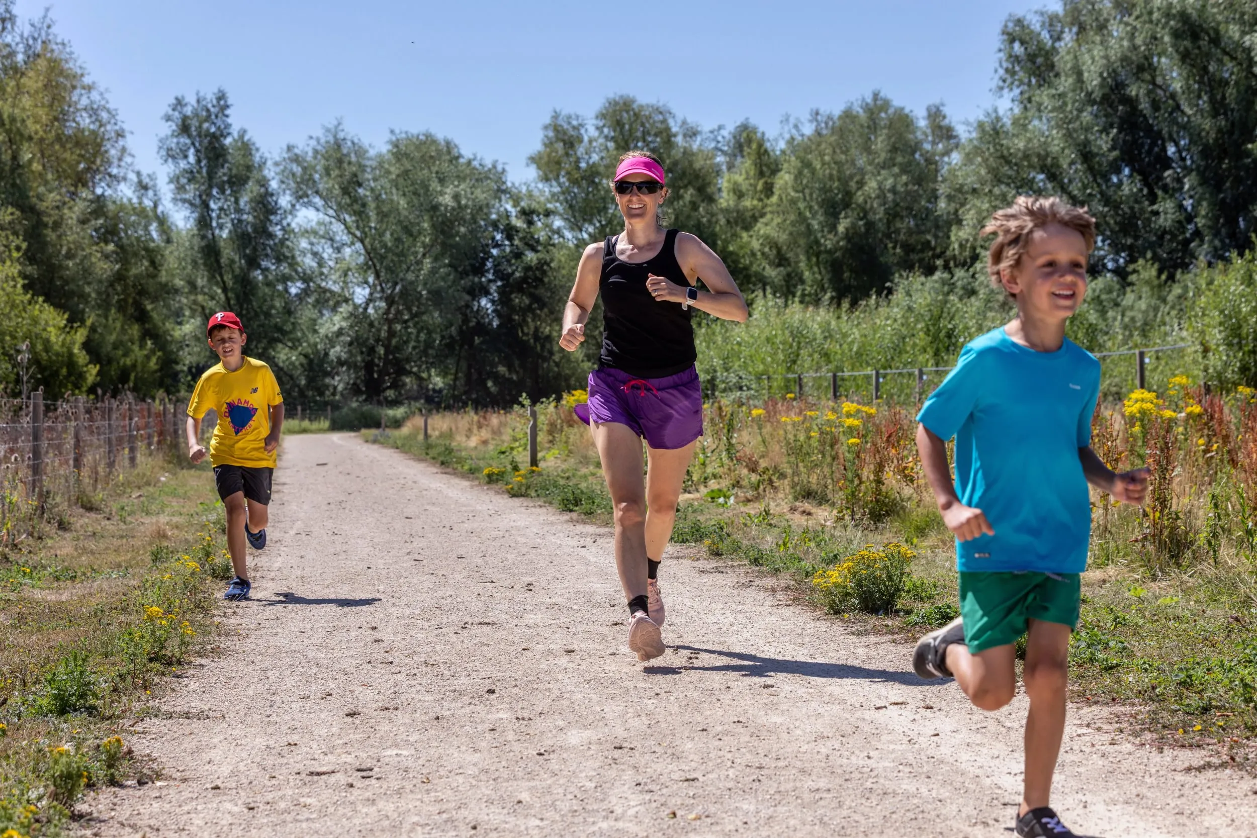 A woman & two boys running down a track.