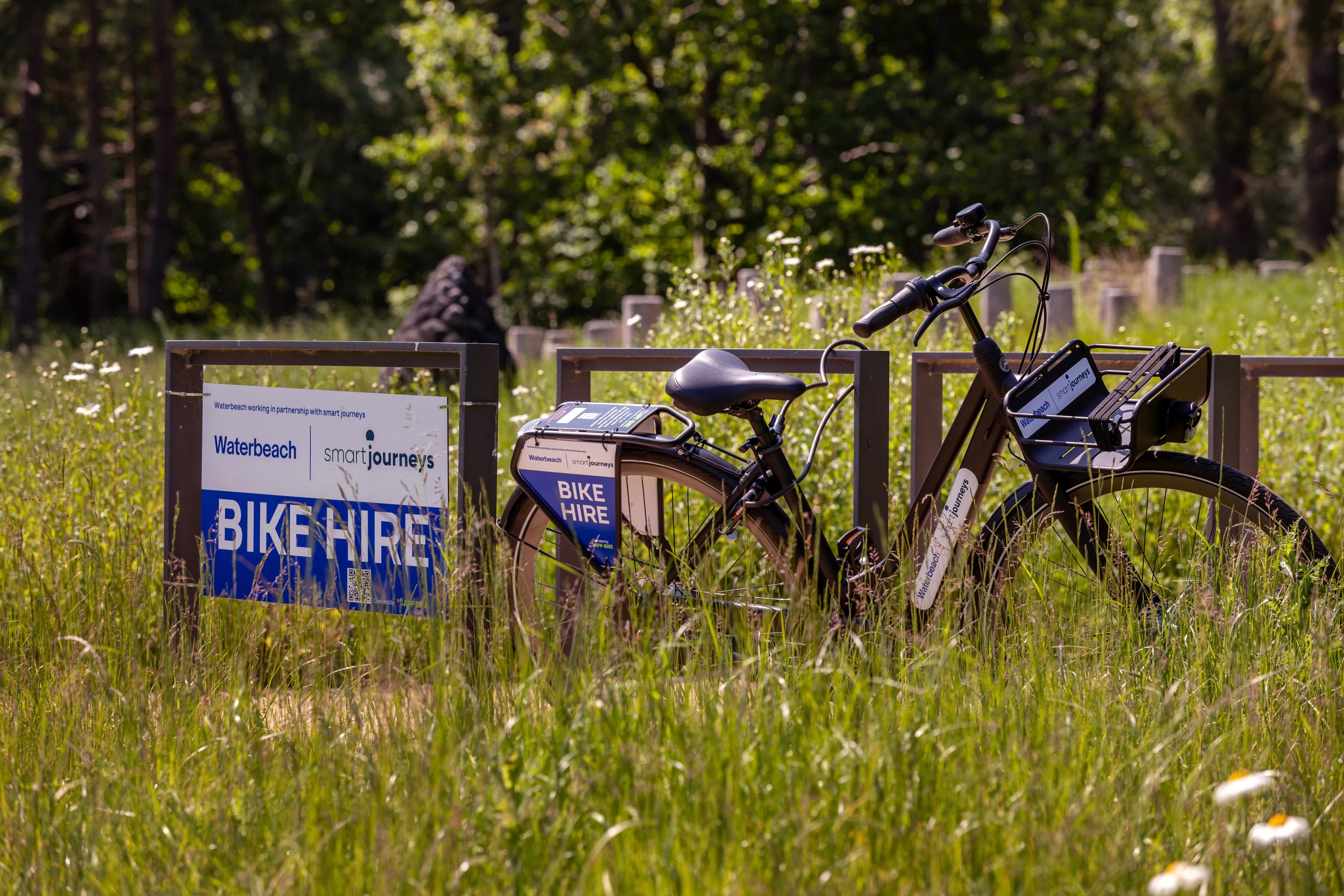 Bike lent against a fence next to a bike hire sign