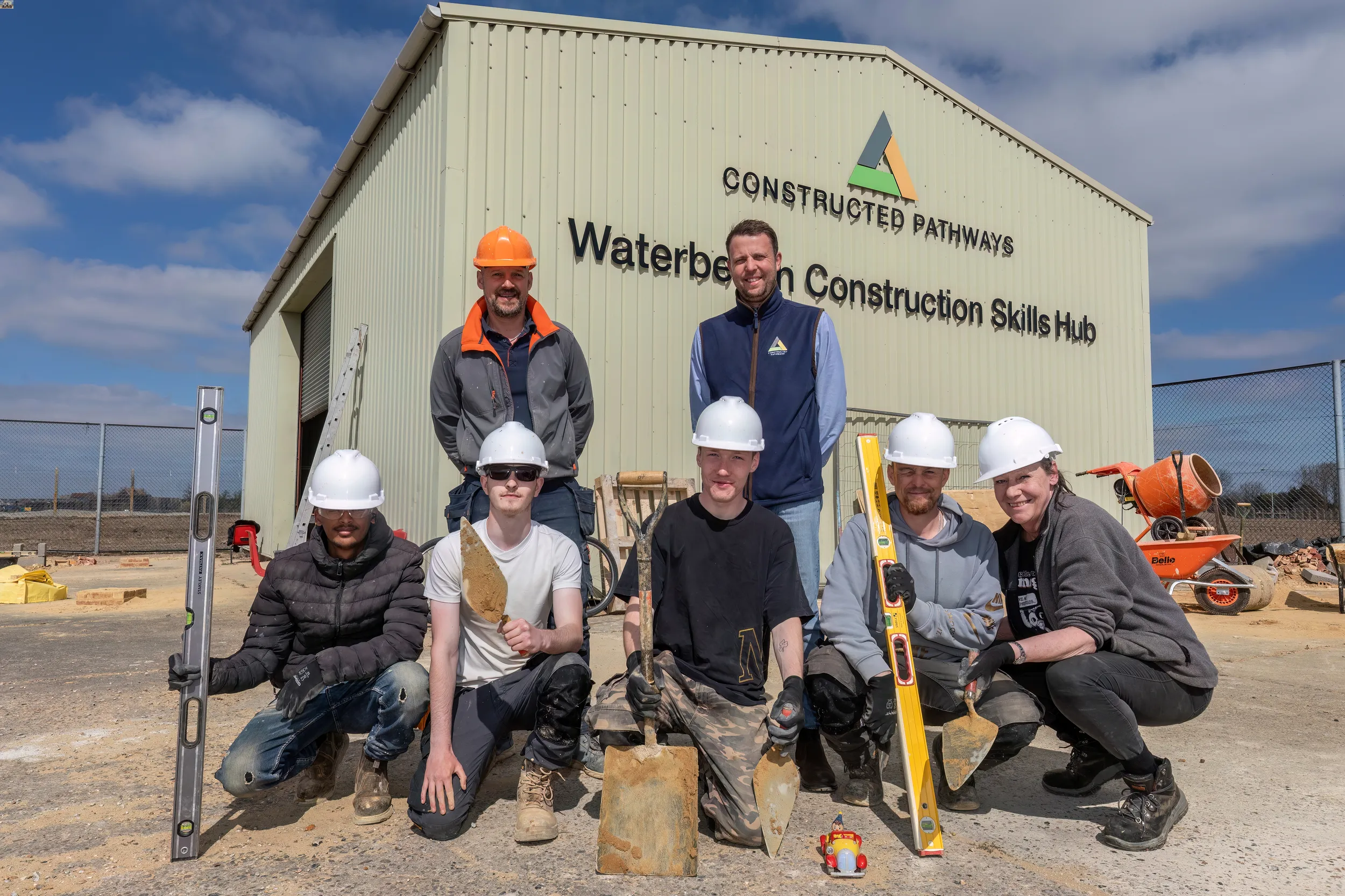 A group of people posing in front of Waterbeach construction skills hub