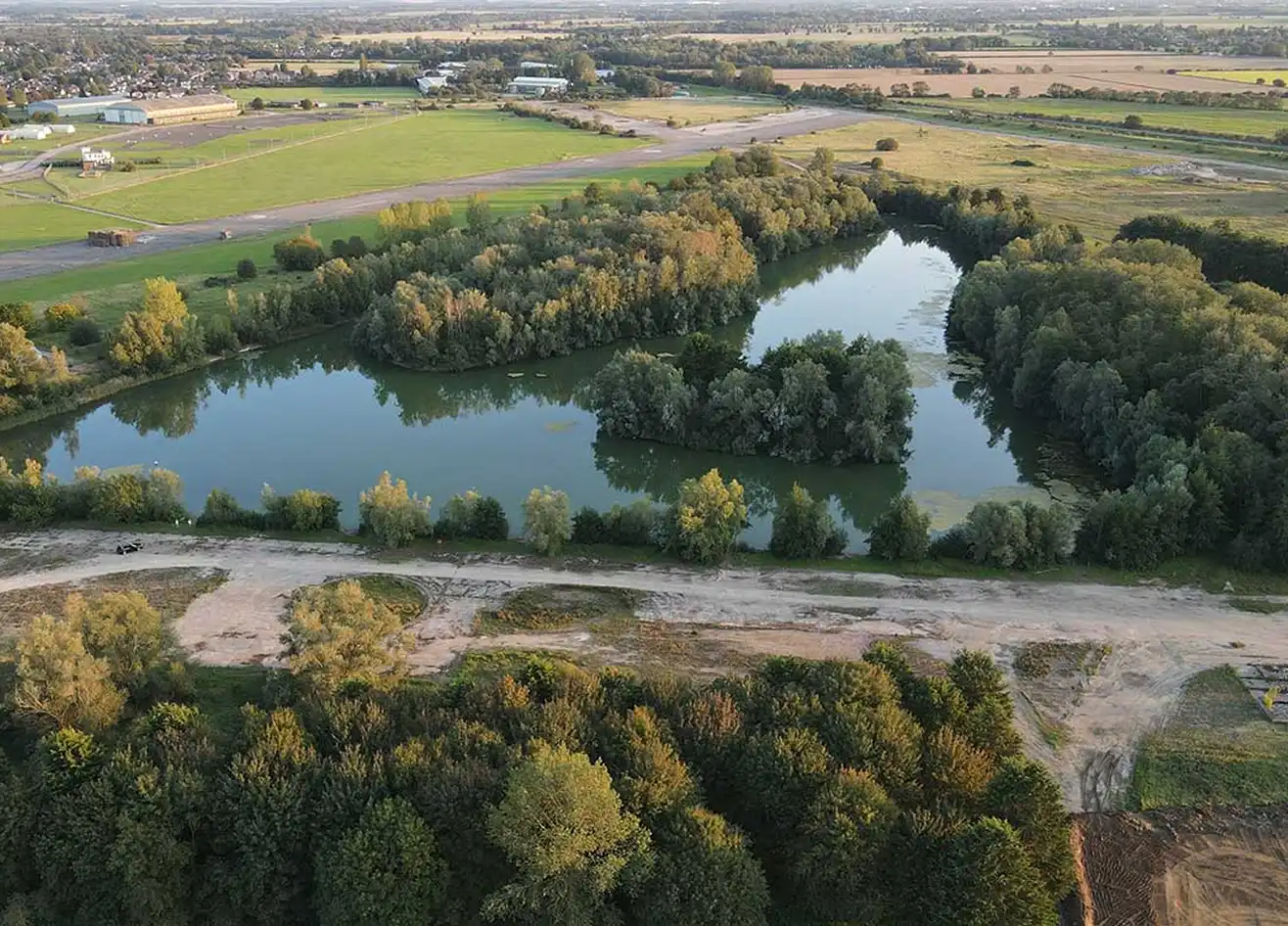Aerial view of the lake at Waterbeach surrounded by farmland and woodland